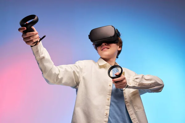 Jeune garçon jouer à des jeux VR en réalité virtuelle casques sur fond lumineux coloré — Photo