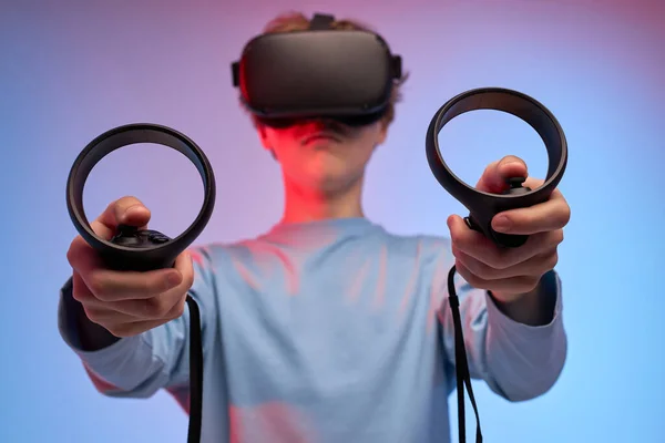 Menino usando capacete VR com controladores em mãos, jogando vídeo gamer sozinho — Fotografia de Stock