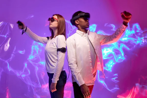 Dos amigos en ropa casual se paran con cascos VR y juegan juegos en realidad virtual — Foto de Stock