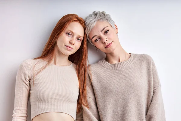 Två vänliga kaukasiska flickvänner i beige ledig skjorta poserar tittar på kameran, känner lugn — Stockfoto