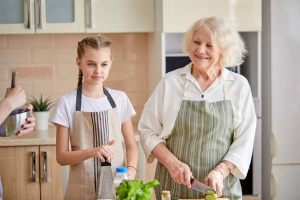 Amigável adulto senhora sênior ensinando menina adolescente como cozinhar comida saudável — Fotografia de Stock