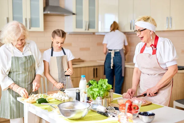 Caucasian grandparents cooking with granddaughters in the kitchen — Stock Photo, Image