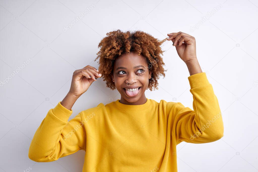 Happy laughing young frican woman with short curly hair on white background, touching hair and looking at side