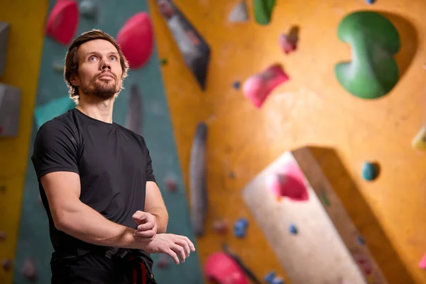 confident professional sport climber man preparing to train in gym at artificial wall