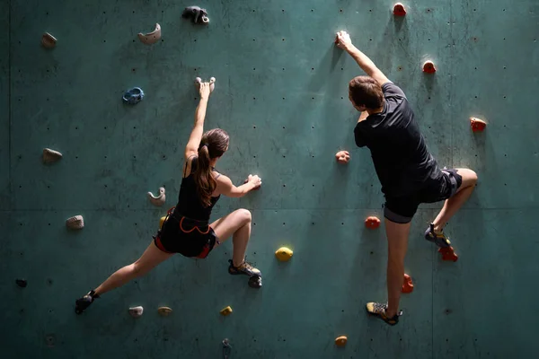 Mužské a ženské cvičení v kryté lezecké tělocvičně společně, s bezpečnostním vybavením — Stock fotografie