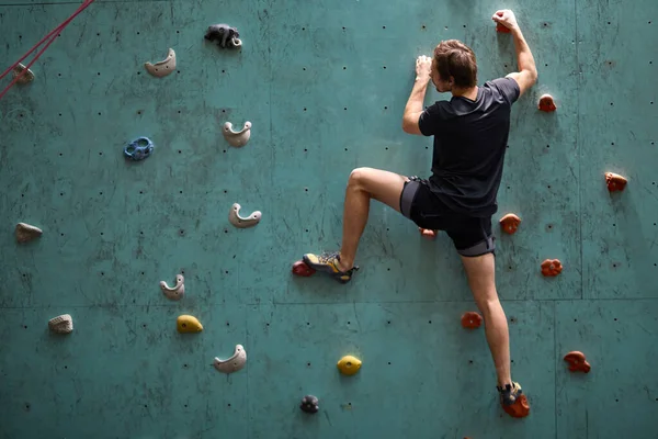 Ekstremalna wspinaczka. Silny człowiek ćwiczący wspinaczkę na sztucznej skale — Zdjęcie stockowe