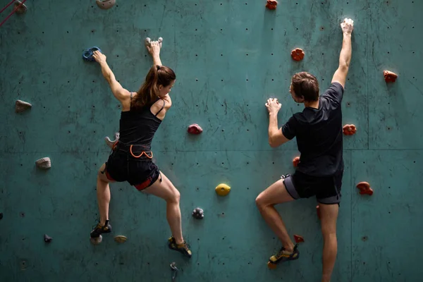 Femme professionnelle et homme alpinistes escalade mur de roche artificielle avec assurage — Photo