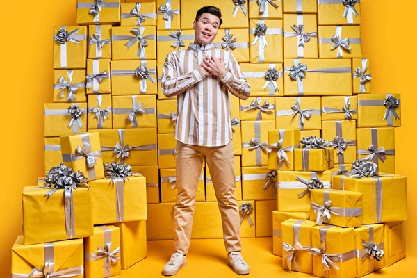 Agradable hombre chino agradecido por recibir tantos regalos regalos, sintiendo gratitud, sosteniendo las manos en el pecho — Foto de Stock