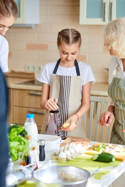 Ευχάριστη γιαγιά που μαθαίνει στο κοριτσάκι να μαγειρεύει, δείχνοντας πως να φτιάχνει νόστιμο φαγητό. — Φωτογραφία Αρχείου