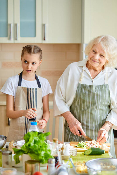 Happy family different generations cooking together, chopping food for lunch