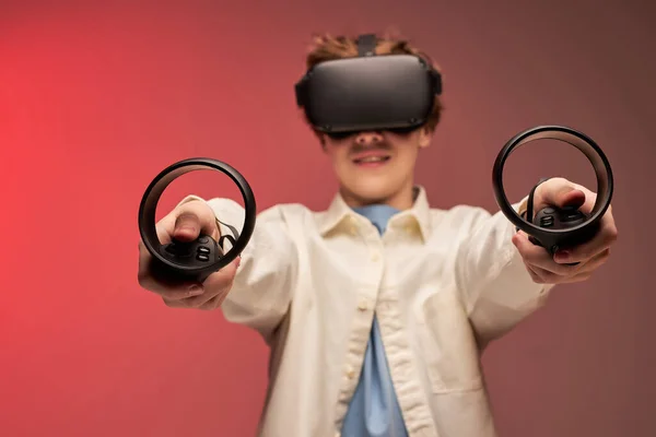 Joyeux garçon jouer à des jeux VR dans des casques de réalité virtuelle sur fond lumineux coloré — Photo