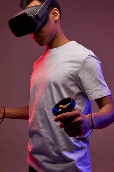 Jeune noir jouer VR jeux en réalité virtuelle casques sur fond lumineux coloré — Photo