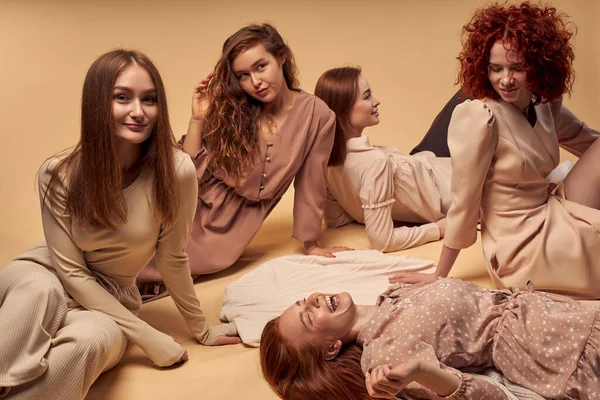 Positiv gelaunte Frauen amüsieren sich im Studio auf dem Boden liegend, in lässigen Outfits — Stockfoto