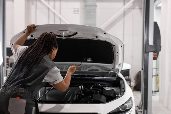 african woman professional master repairing car in workshop at workplace