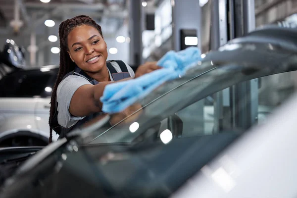 Vrouwelijke Afrikaanse auto monteur reiniger is het reinigen van auto glas met vod — Stockfoto