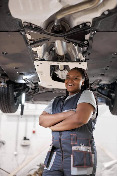Professionele zwarte vrouwelijke monteur poseren op camera staande in auto reparatiewerkplaats — Stockfoto
