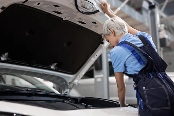 Jonge vrouwelijke auto reparateur. Vrouwelijke monteur controleert het oliepeil in de automotor — Stockfoto