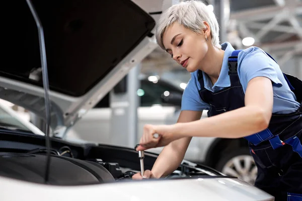 Blanke vrouw onder de motorkap. vrouw in uniform monteur reparatie auto — Stockfoto