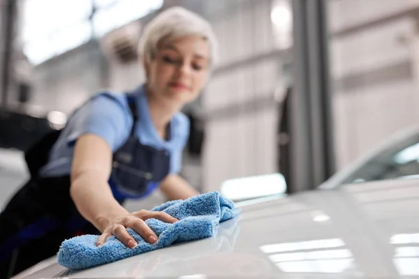 Крупным планом руки женщины полируют капот белой машины синей тряпкой после мытья — стоковое фото