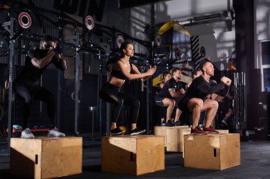 Spor salonunda tahta kutuya atlayan insanların yan görüntüsü