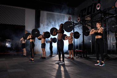 Kas Sporu yapan insanlar birlikte halter egzersizi yapıyorlar.