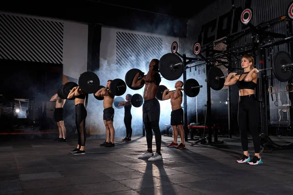 Kas Sporu yapan insanlar birlikte halter egzersizi yapıyorlar.