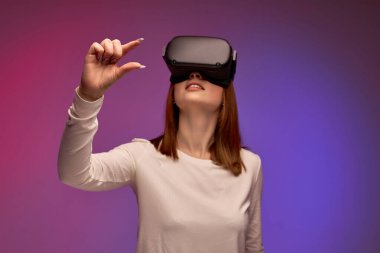VR teknolojileri. Sanal gerçeklikteki genç kadın ellerini havada tutuyor.