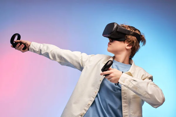 Portrait de jeune homme dans le casque VR tenant le dispositif dans les mains sur fond coloré — Photo