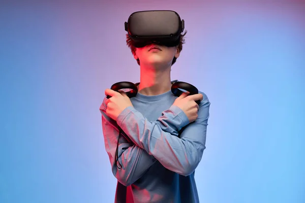 Adolescent incroyable dans vr lunettes casque tenant contrôleurs, gardant les mains croisées — Photo