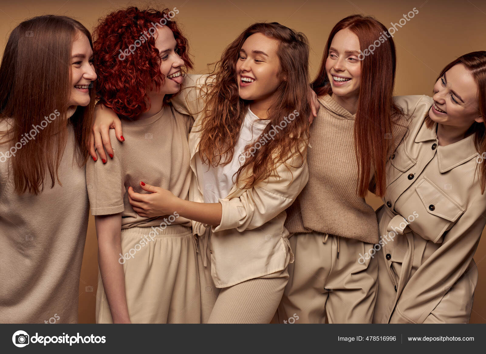 Grupo de alegre pelirroja damas en beige ropa de moda posando