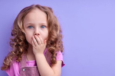 Şok olmuş genç kızın portresi. Mor renkte izole edilmiş ağzıyla el ele tutuşan çılgın kız.