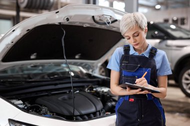 Pano ve kalem yazısıyla üniformalı beyaz bir kadın işçi.