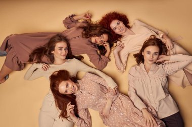 Mutlu beyaz kadınlar stüdyoda yerde yatıyor, arkadaşlığın, boş zamanların tadını çıkarıyorlar.