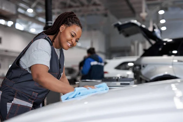 Afro vrouw polijsten schoonmaken auto met microvezel doek, auto detaillering of valeting concept — Stockfoto