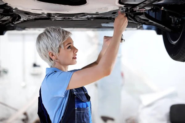 Professionella kvinnliga mekaniker som håller fast underrede av fordon — Stockfoto