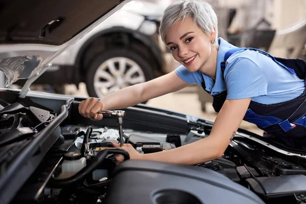 Усміхнена жінка під капотом автомобіля. жінка в уніформі механічного ремонту автомобіля — стокове фото