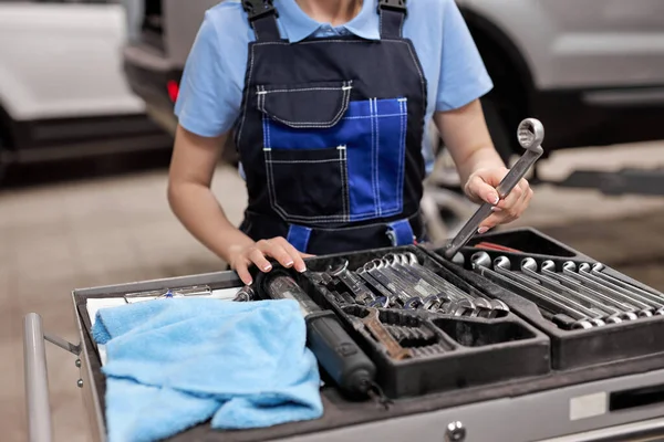 Обрезанный неузнаваемый женский автомеханик, берущий инструменты для ремонта автомобилей — стоковое фото