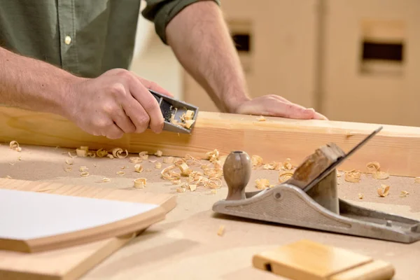 Joiners obras: mãos de carpinteiro masculino rabisca a placa com plaina, em oficina — Fotografia de Stock