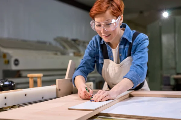 Feminino carpinteiro em linha de desenho camisa azul com uma ferramenta de medição, na prancha de madeira — Fotografia de Stock