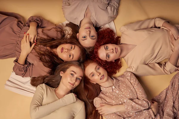 매력적 인 모델들 과 친구들, 길고 빨간 머리를 한 자매들 이 베이지 색 배경 위에 누워 있다 — 스톡 사진
