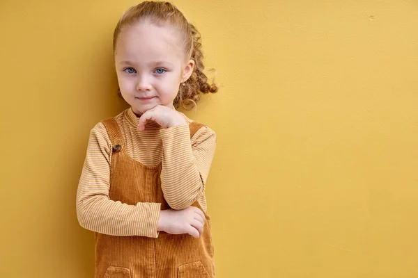 긍정적 인 미소를 짓는 어린이 소녀 - 노란 스튜디오 배경에서 격리, 시계를 참조하 십시오. — 스톡 사진