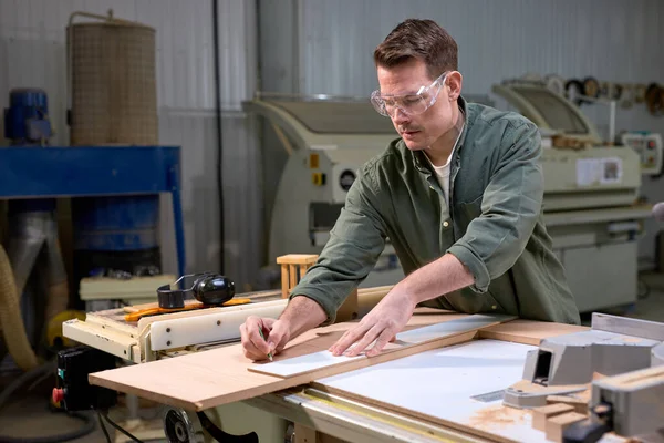 Carpenter confiante trabalhando com equipamentos em mesa de madeira na loja de carpintaria — Fotografia de Stock