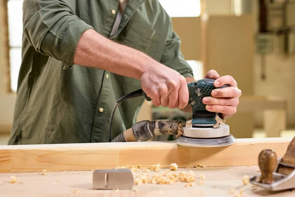 Hands of joiner worker using electric sander in workshop, sanding wooden board — Stock Photo, Image