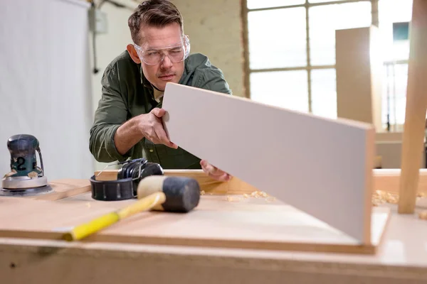 Carpinteiro profissional comparando, verificando o comprimento e a superfície do material de madeira — Fotografia de Stock