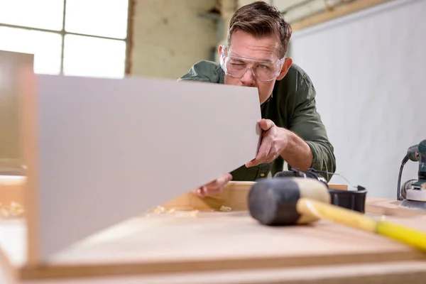 Carpinteiro masculino em óculos de inspeção de trabalho após o tratamento de madeira com tinta de proteção — Fotografia de Stock