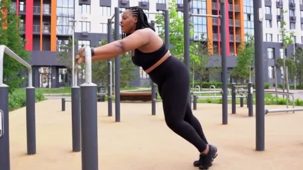 Atraente plus size afro-americano feminino alongamento pernas fazendo exercícios. ao ar livre na cidade — Vídeo de Stock