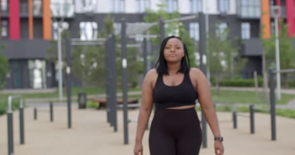 Más tamaño corredor femenino posando en traje de correr en la ciudad en el campo de deportes después del entrenamiento — Vídeo de stock