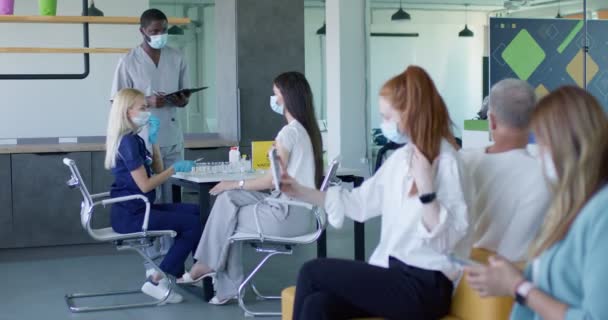 大規模予防接種を待つ病院の列に座っている患者 — ストック動画
