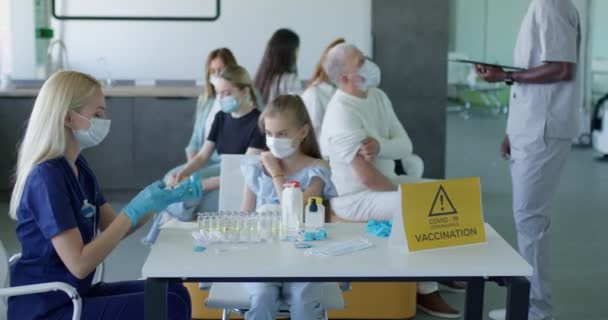 Beyaz kadın, çocuk kıza koronavirüs aşısı yapıyor. Büyükbabasıyla gelmiş. — Stok video