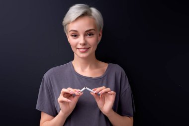 Sigara içmeyi bırak. Elinde kırık sigara tutan bir kadının portresi.